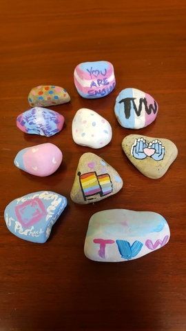 rocks with paintings of positive trans symbols and expressions on them