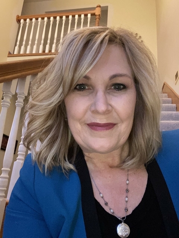 Headshot of a woman sitting at the base of the stairs looking at the camera.