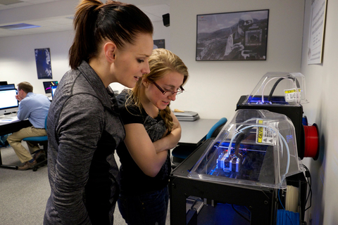 Two students watching 3D printer print