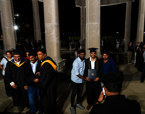 Students pose in front of a crowded Colonnade after graduation.