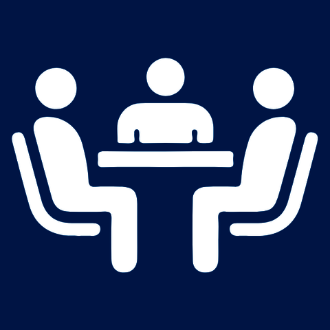 White icon of people sitting with another person at a desk, with blue background.
