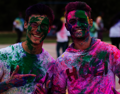 Two students, covered in pink and green powder, pose for the camera.