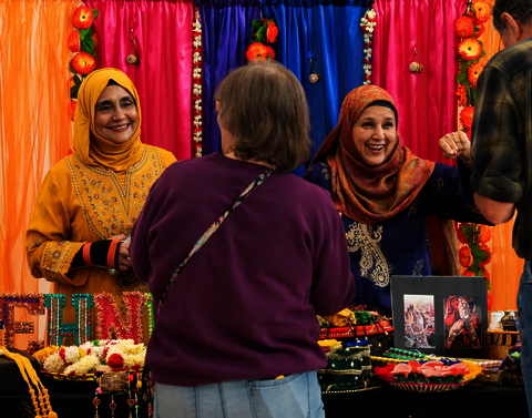 Women in colorful hijabs greeting guests.