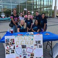 The MLS club at a table in front of the Student Union with a poster about the club.