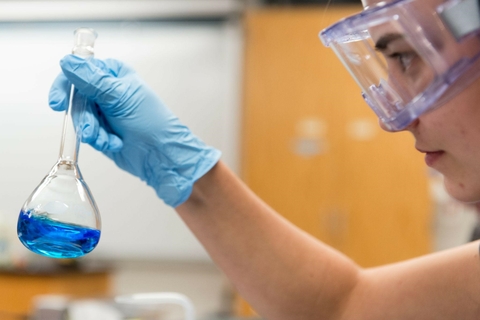 student holding a beaker with liquid in it