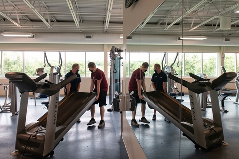 Sports Management students adjusting workout equipment