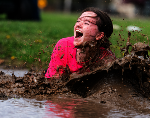 A student smiles while plunging into mud.