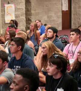 students sitting on the floor listening to a speaker