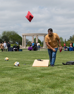 Students play lawn games during a campus health fair on the UIS quad, with booths and the colonnade visible in the background.