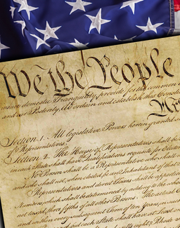 Close-up of the United States Constitution with the words “We the People” visible, placed over an American flag background.