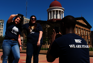 Three people outside posing for a photo in front of a historic building.
