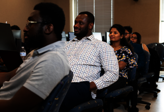 People seated in a classroom, attentively looking forward.