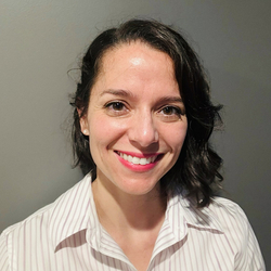 Smiling woman in a striped shirt against a gray background