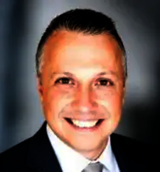 Smiling man in a suit against a dark background