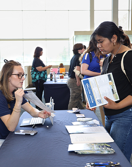 Woman at table discussing brochures with an attendee at an event.