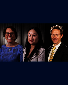 Three people in formal attire, smiling in a dark studio setting.