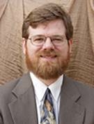 Man looking at the camera wearing a suit and glasses.