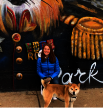 Dr. Magic Wade pictured with her dog in front of a painted mural of a fox on a brick wall