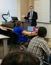 Professor Serkan Karadas teaches a class with three students visible in the photo.