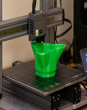 A 3D printer printing a green three petal dish at the Orion Lab at the University of Illinois Springfield