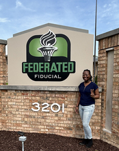 UIS student Wonder Odutola stands next to Federated Fiducial sign.