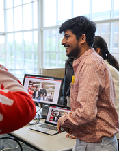 Student smiles while presenting a project on a laptop during a campus event.