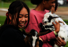 Two students holding goats