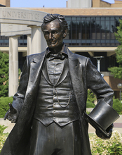 Statue of Abraham Lincoln with the UIS colonnade in the background.