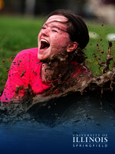 A girl smiles as she plunges into the mud.