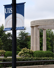 University Colonnade and a UIS banner, overcast sky.