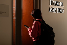 Person with a backpack entering a financial assistance office