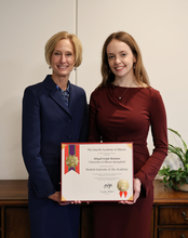 Two women smiling with an award certificate in a professional setting.