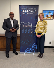 Two people standing beside a University of Illinois banner indoors.