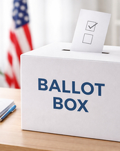 Ballot box on table with envelope, American flag in background.