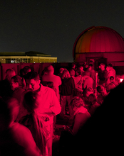 A large group of people on the roof of UIS Brookens Library at night with red lights.