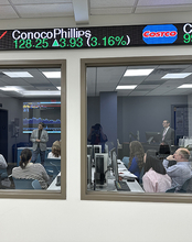 People in a conference room watching a financial presentation.