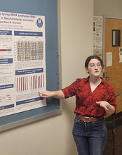 Woman presenting a research poster in a classroom setting.