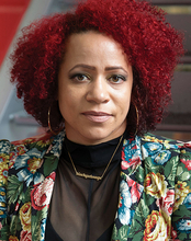 A woman with curly red hair, wearing a floral jacket and hoop earrings.