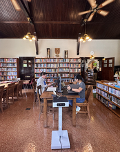 Cozy library with two people working at a wooden table, surrounded by bookshelves.