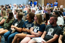 Audience seated attentively in a conference room.