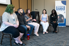 Panel discussion with five seated people in a conference room.