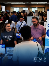People engaging at a university career fair booth.