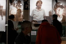 Exhibition with large portraits of people, dark silhouettes in foreground.