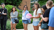 Group of young adults outdoors, one holding a colorful beach ball.