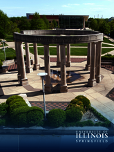 Circular stone structure on a campus with surrounding greenery.