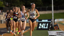Maddie Miller-Ross running an outdoor track race in gold UIS uniform