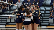 UIS Volleyball team in a huddle on the court