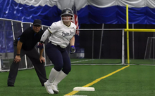 Emme Steward on third base at softball tournament in Springfield Clinic Dome, wearing white and blue UIS Prairie Stars uniform