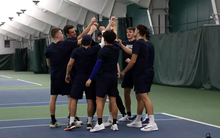 UIS men's tennis team in a huddle at indoor facility