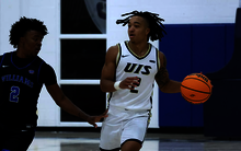 Jordan Rice playing basketball in white UIS uniform
